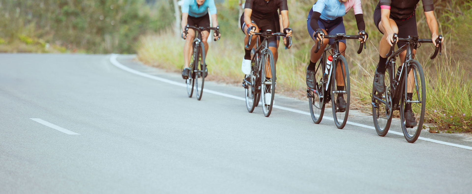 A group of four road cyclists during a ride on an asphalt road.